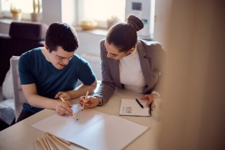 A man and woman sit at a table working on co-designing the NDIS bill