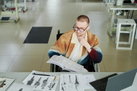 man with bright orange poncho is reading the new NDIS Bill, He has a pensive look about him