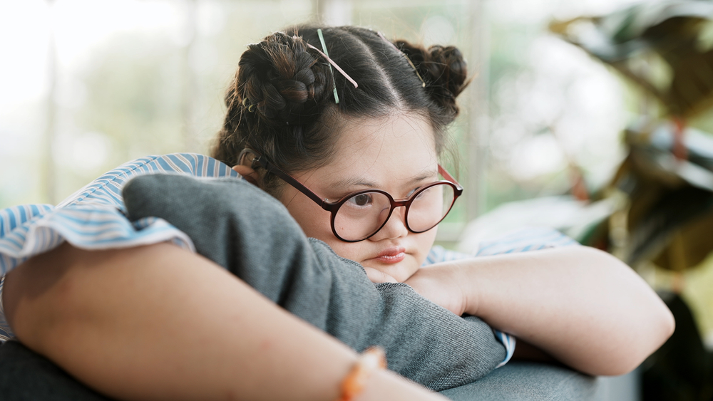 A young woman with glasses and laya hair reflects on how the NDIS list changes will affect her.