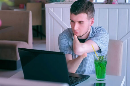 A young man with amputated hands talks on video chat on his laptop. He's attending a NDIS Co-Design meeting