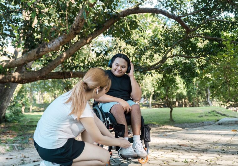 a woman is fussing over a mans shoes, the man is in a wheelchair. They are talking about a Change of Details and SDA for his NDIS plan